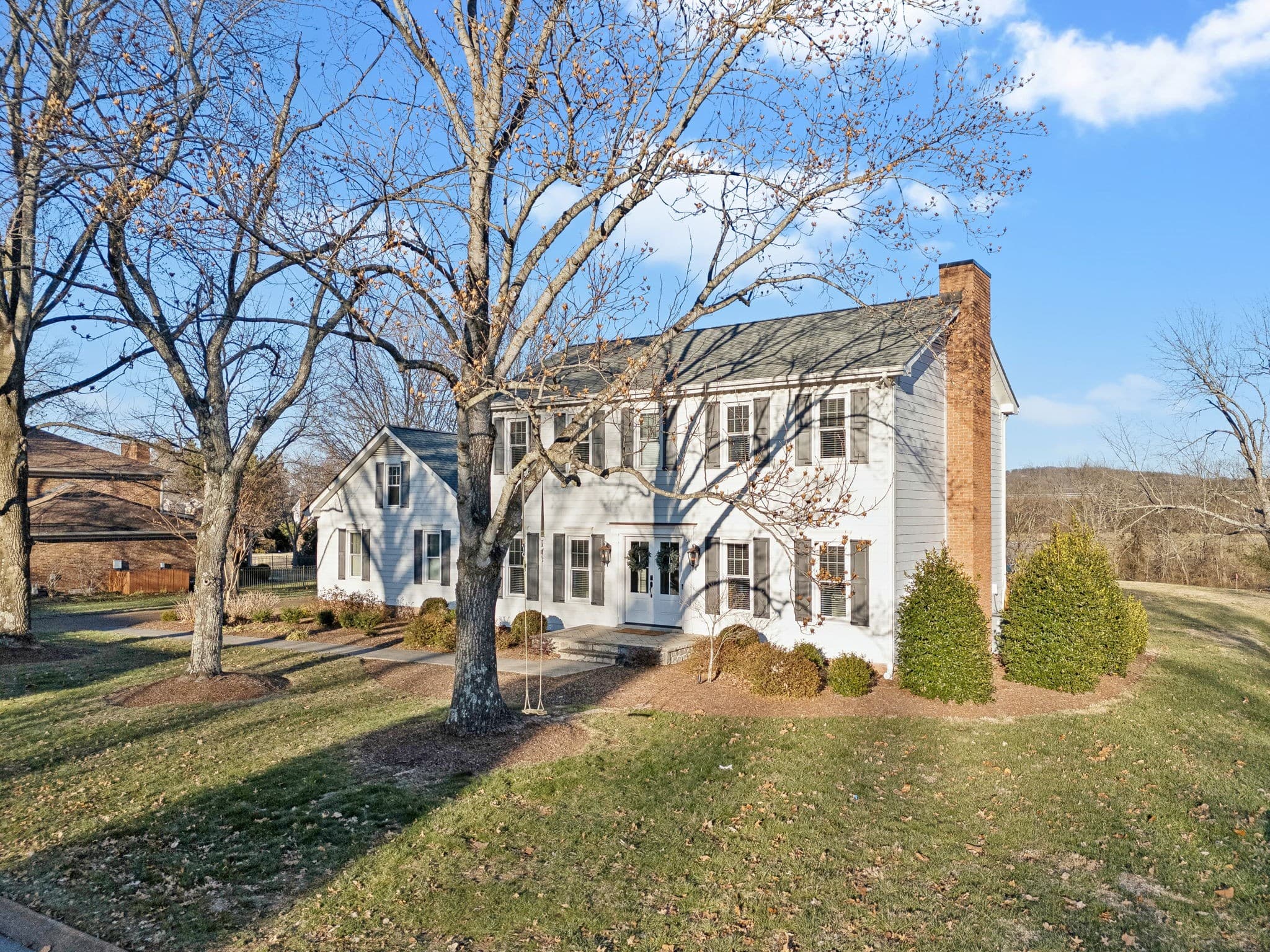 Sold: white colonial with black shutters and a brick chimney on a sloping Brentwood lawn